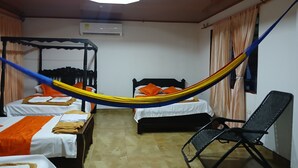 A room with two beds, a chair, and a ceiling fan.