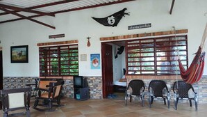 A room with a tiled floor, a wooden ceiling, a hammock, a television, and a sign that reads "La familia lo es Todo".