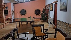 A spacious indoor area with a high ceiling, a central seating area with multiple chairs, and a wall adorned with framed pictures.