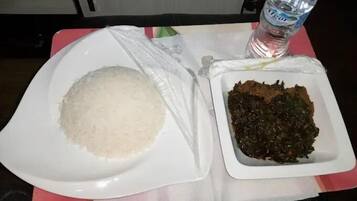A plate of white rice and a bowl of dark green vegetables on a table with a water bottle.