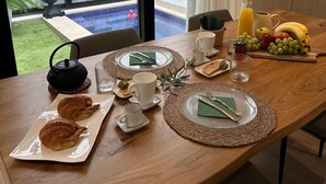 A breakfast table set with croissants, coffee, and fruit, overlooking a swimming pool. - Náquera Rural House in the Town Center with Pool (Nàquera)