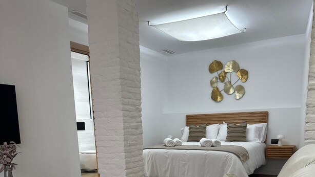 A modern bedroom with a large bed, a white sofa, and a decorative wall piece. - Náquera Rural House in the Town Center with Pool (Nàquera)