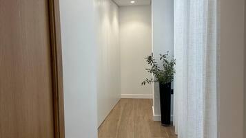 Un passadís amb sòl de fusta, parets blanques i una planta en test.