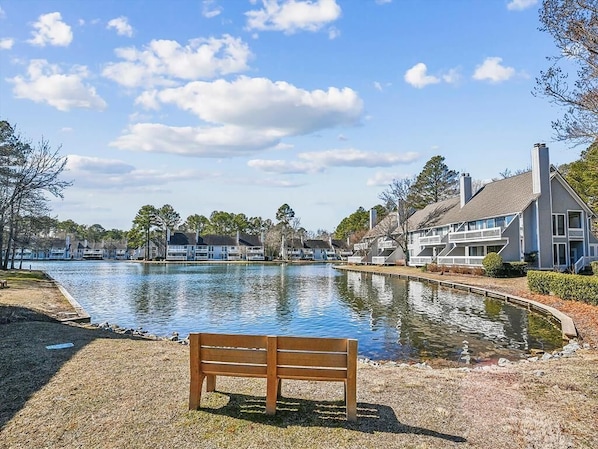 Un banc situé au bord du lac, offrant une vue sur le lac paisible et sur les immeubles résidentiels qui se dressent à l’arrière-plan.