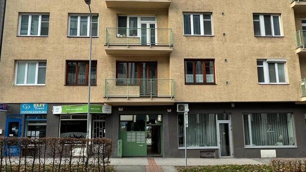 Een meerlaags gebouw met balkons, een winkel en een groen luifel.