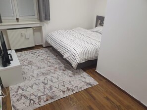A bedroom with a bed, a radiator, a small plant, and a patterned rug. - Charming 2 Bedroom Apartment in Bratislava (Bratislava)