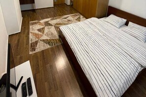 Une chambre d’hôtel avec un lit, un plancher en bois et un tapis à motifs.