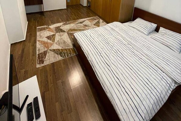 Une chambre d’hôtel avec un lit, un plancher en bois et un tapis à motifs.