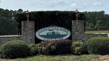 A sign for Pankatank River Golf Club with a stone wall and two lanterns.