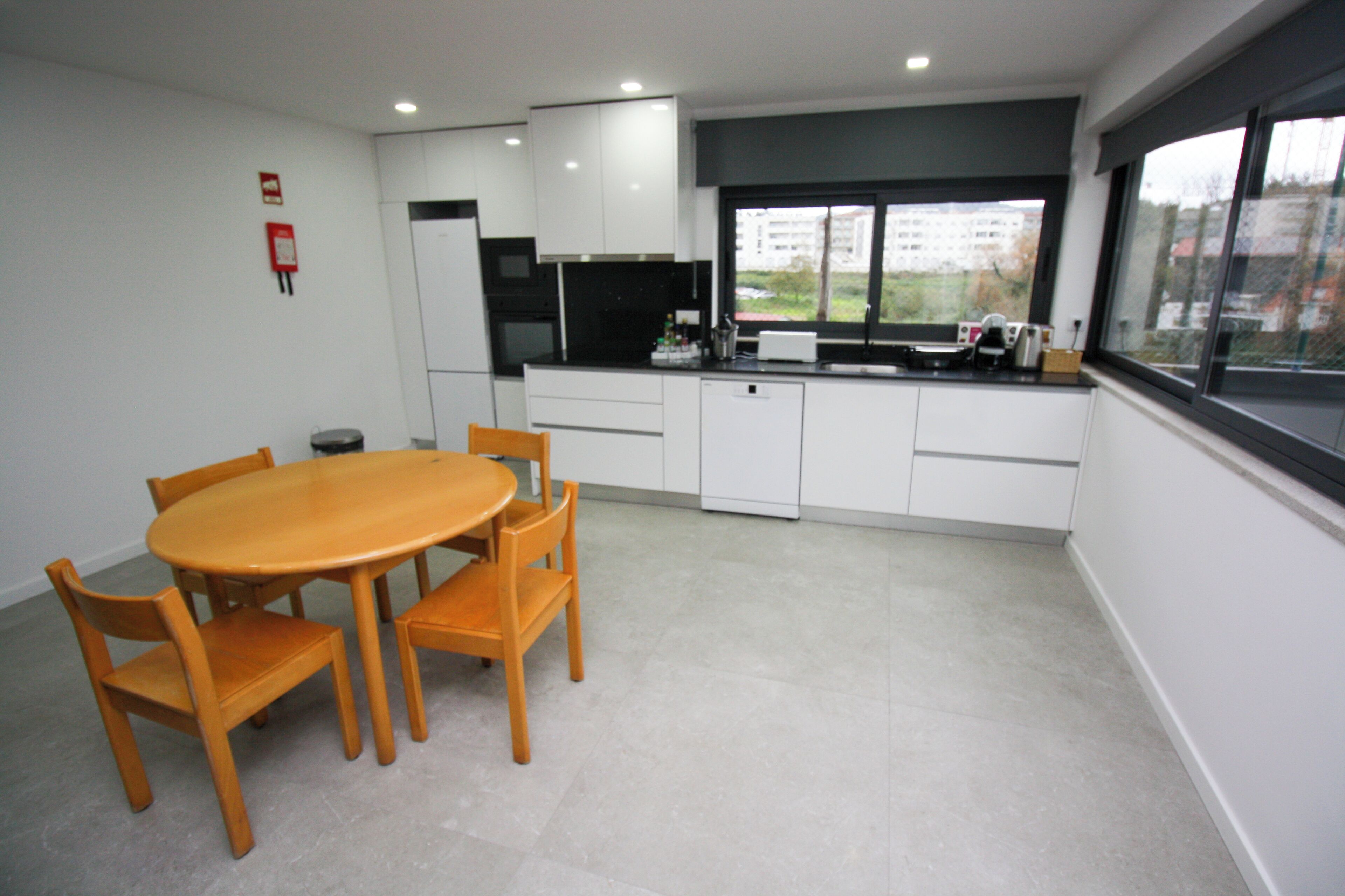 Una cocina moderna con gabinetes blancos, encimera negra y ventana con vistas a edificios.