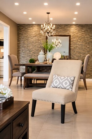 Un comedor moderno con candelabro, pared de piedra y mesa con sillas.