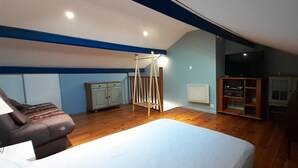 Une chambre à coucher avec un lit, une armoire en bois, un téléviseur et un ventilateur de plafond.
