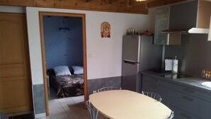 Une cuisine compacte avec une table et des chaises, un réfrigérateur, et un lit dans la pièce adjacente.