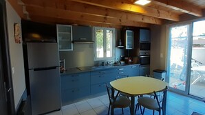 Une cuisine de taille réduite comprenant un réfrigérateur, des placards et une table à manger.