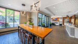 Un moderno vestíbulo de hotel con un mostrador de recepción de madera, taburetes de bar, ventanas amplias y una chimenea.