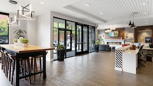 Un vestíbulo de hotel moderno con un mostrador de recepción de madera, asientos de bar y una chimenea.