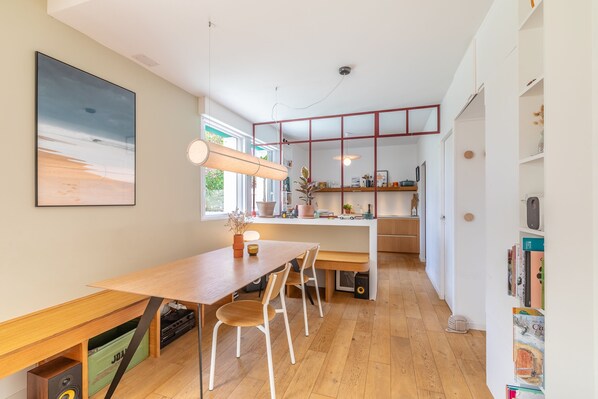 Una cocina moderna con suelo de madera, una isla central y un comedor con sillas.