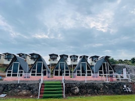 Fileira de edifícios modernos com telhados triangulares, grandes janelas e um muro de pedra em primeiro plano.