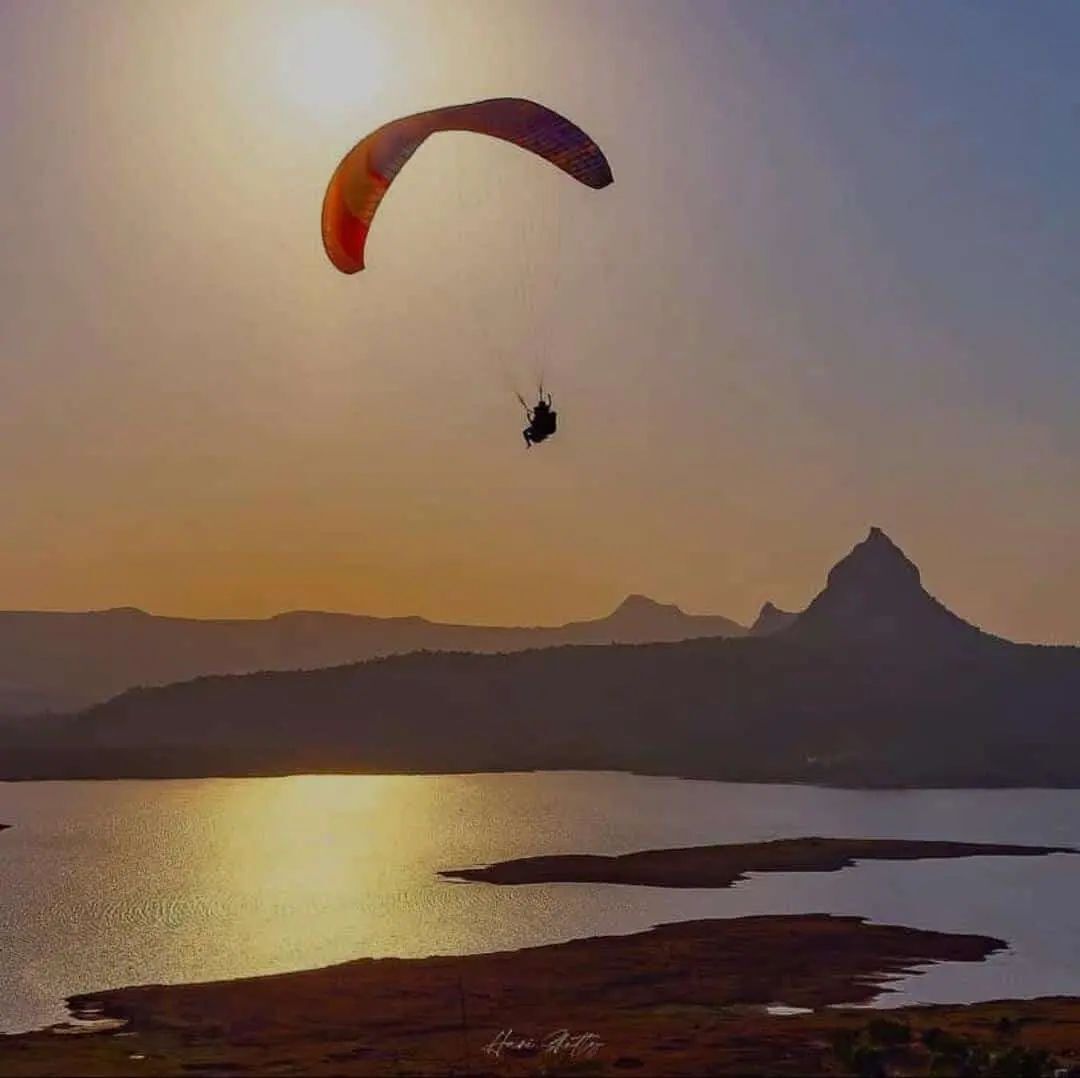 A paraglider flying over a body of water with mountains in the background.