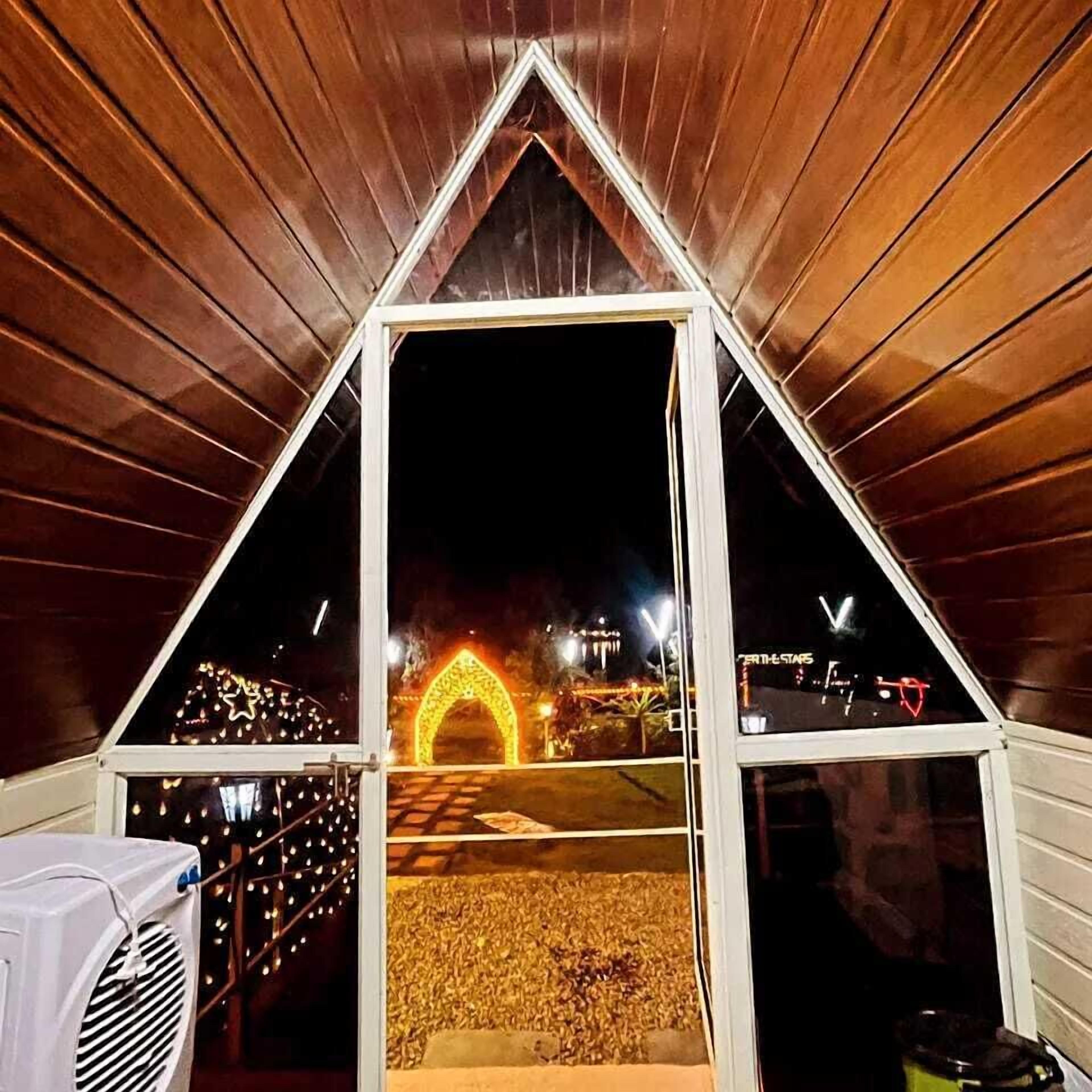 A triangular structure with a dark interior and a view of a lit archway outside.