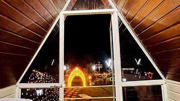 A triangular structure with a dark interior and a view of a lit archway outside.