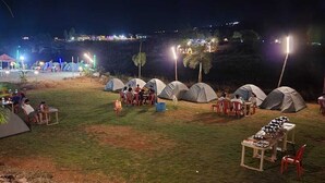 Un camping con tiendas de campaña, mesas y sillas dispuestas para comer.