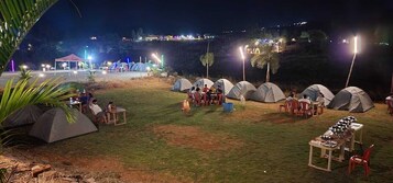 Um camping com tendas, mesas e cadeiras dispostas para refeições.