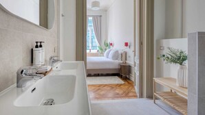 A modern bathroom with a large white bathtub, a mirror, and toiletries on the wall. - Deluxe Loft Mas C-12 (Brussels)