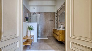 A modern bathroom with a shower, vanity, and a small shelf with a vase. - Deluxe Loft Mas C-12 (Brussels)