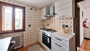 A compact kitchen with a gas stove, oven, and modern cabinetry. - Cozy 2nd floor apartment with terrace (Venezia)