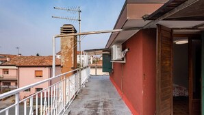 A narrow balcony with a metal railing, an air conditioning unit, and a door leading to a room with a bed. - Cozy 2nd floor apartment with terrace (Venezia)