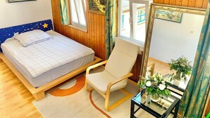 Une chambre à coucher avec un lit, une chaise, un miroir et une fenêtre avec des rideaux.