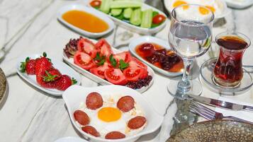Uma mesa posta com diversos pratos, incluindo tomates fatiados, morangos e um prato com ovos e pepperoni.