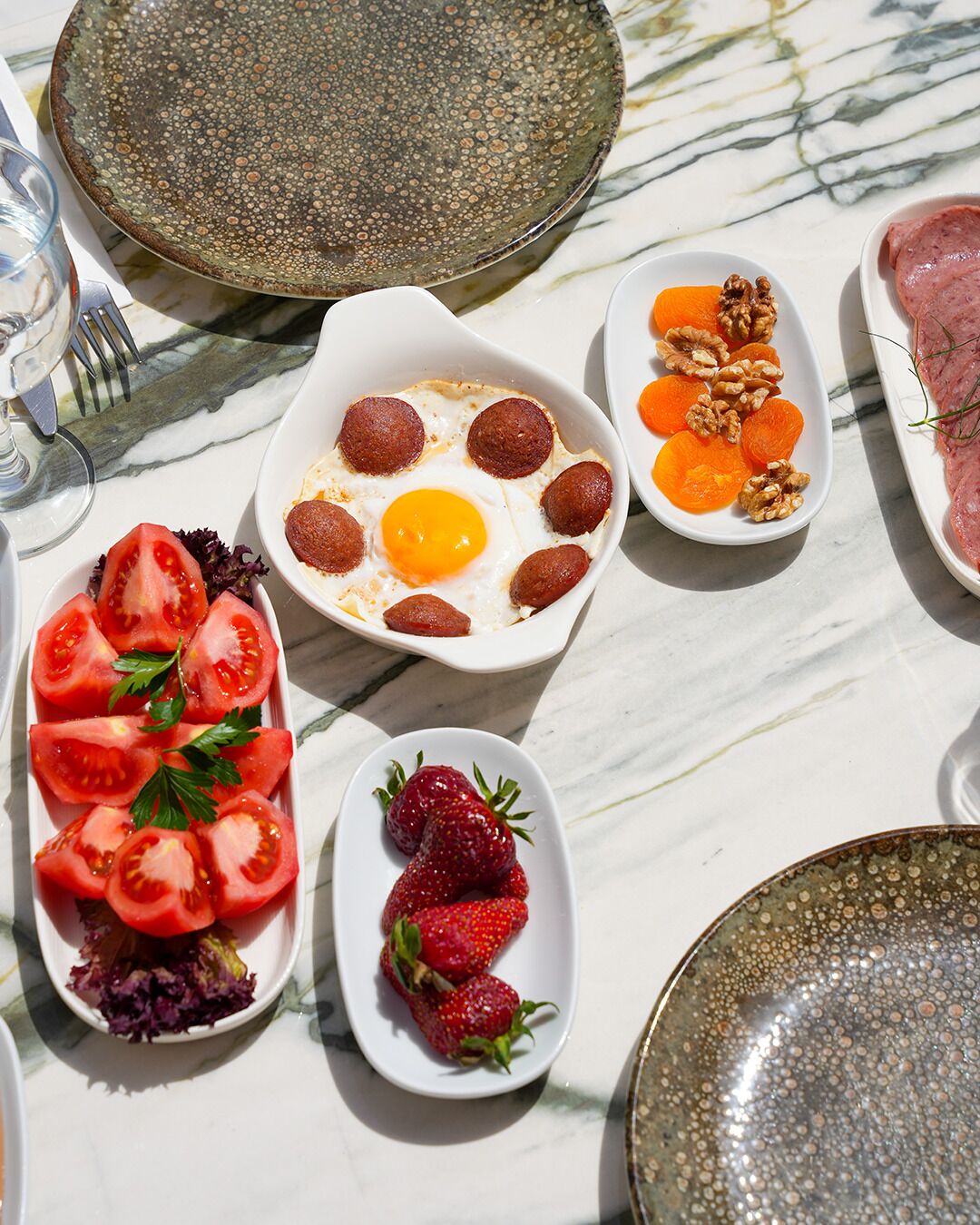 Un desayuno con platos de huevos, tomates, fresas y nueces.