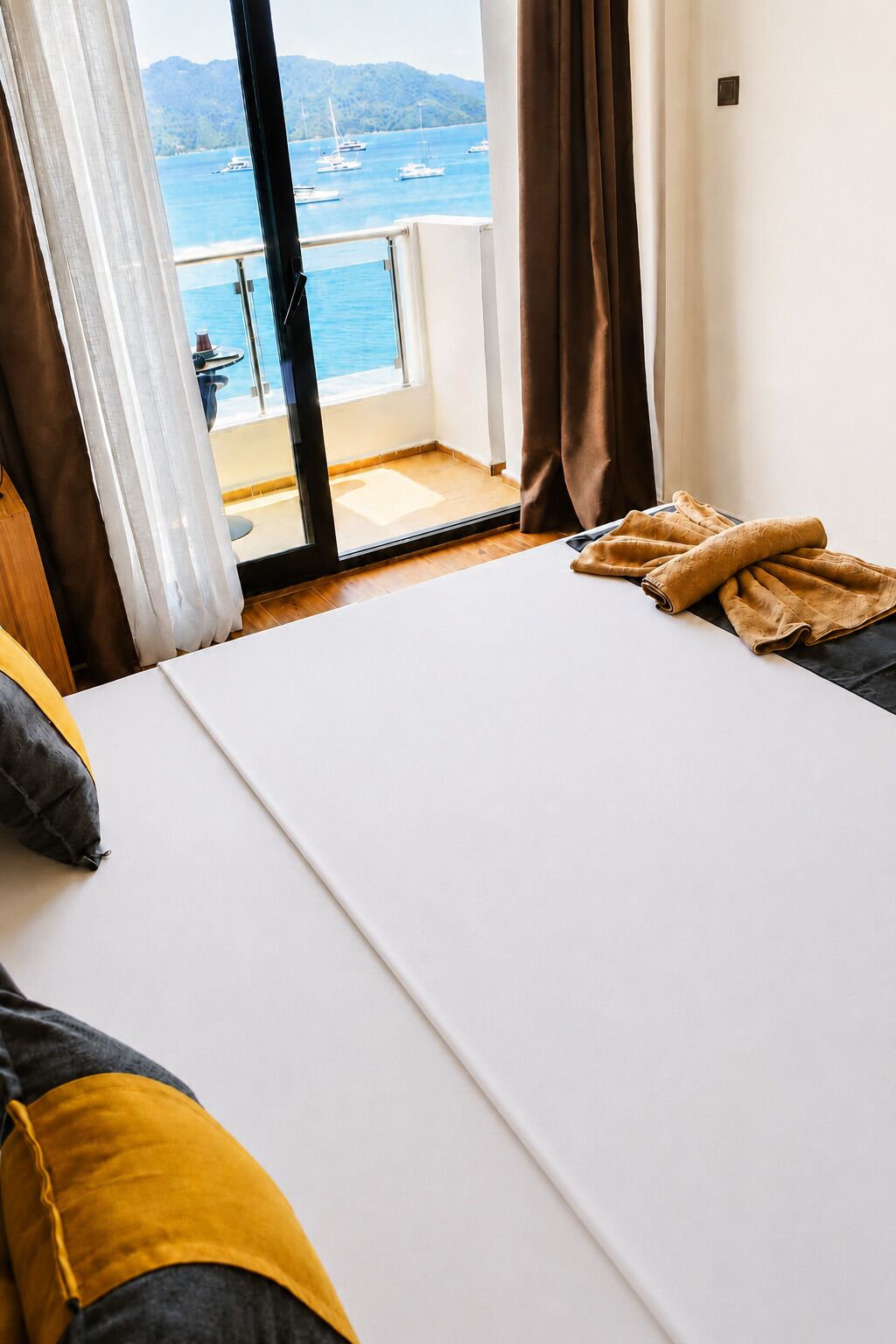 A bedroom with a large bed, a view of the sea, and a balcony.