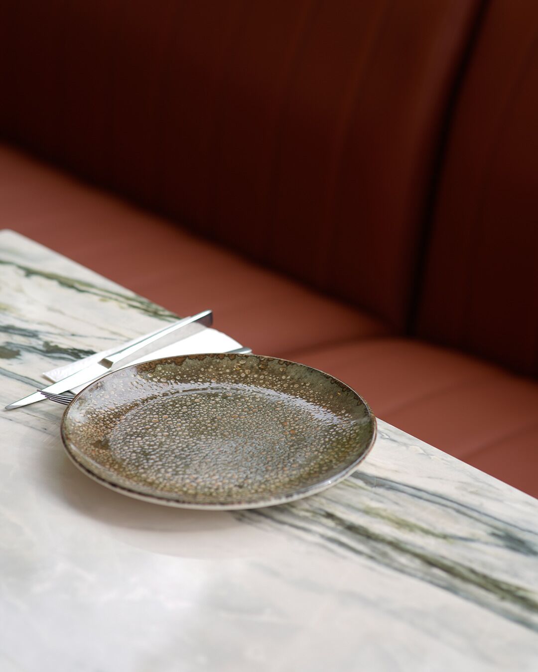 Une assiette en céramique sur une table en marbre, avec une fourchette à côté.