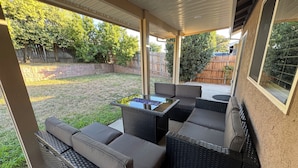 A covered patio area with wicker furniture and a glass-top table. - Charming 3-bedroom Private Home in the Heart of Sacramento (Sacramento)