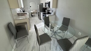 A modern kitchen with white cabinetry, a built-in oven, and a glass dining table with four chairs. - Charming 3-bedroom Private Home in the Heart of Sacramento (Sacramento)