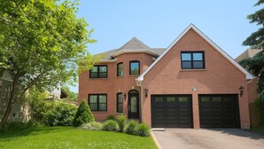 A two-story brick house with a large garage, a well-maintained lawn, and mature trees. - Luxury home 4BR, Pool, & 5 Mins to 401 (Whitby)