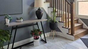 A staircase with wooden balusters, a black vase, and potted plants on a console table. - Luxury home 4BR, Pool, & 5 Mins to 401 (Whitby)