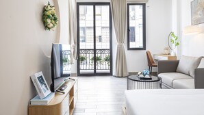 Una habitación de hotel moderna con cama, escritorio, silla, mesa de centro y balcón con vistas.