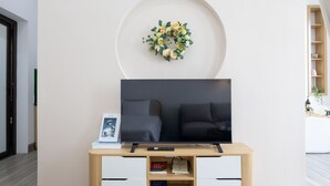 Una sala de estar moderna con un televisor de pantalla plana sobre un mueble de madera, una estantería con libros y una guirnalda decorativa en la pared.