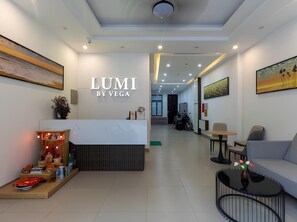 Un espace d’accueil moderne comprenant un comptoir de réception, un coin salon et des œuvres d’art accrochées aux murs.