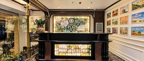 A reception area with a marble floor, a reception desk, and framed pictures on the wall.