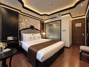A hotel room with a large bed, a nightstand, a desk, and a chair. - Luxury Place Hotel (Hanoi)