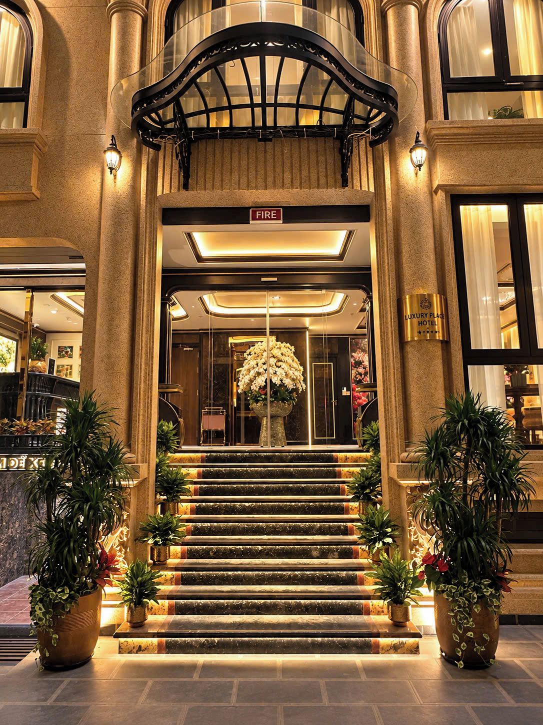 Una entrada imponente con un letrero que dice 'FIRE', un gran arreglo floral y un letrero que indica 'LUXURY PLACE HOTEL'.