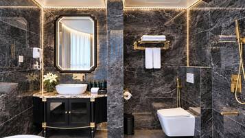 Un baño moderno con una bañera independiente, un tocador con un espejo grande y una zona de ducha con cabezal dorado.