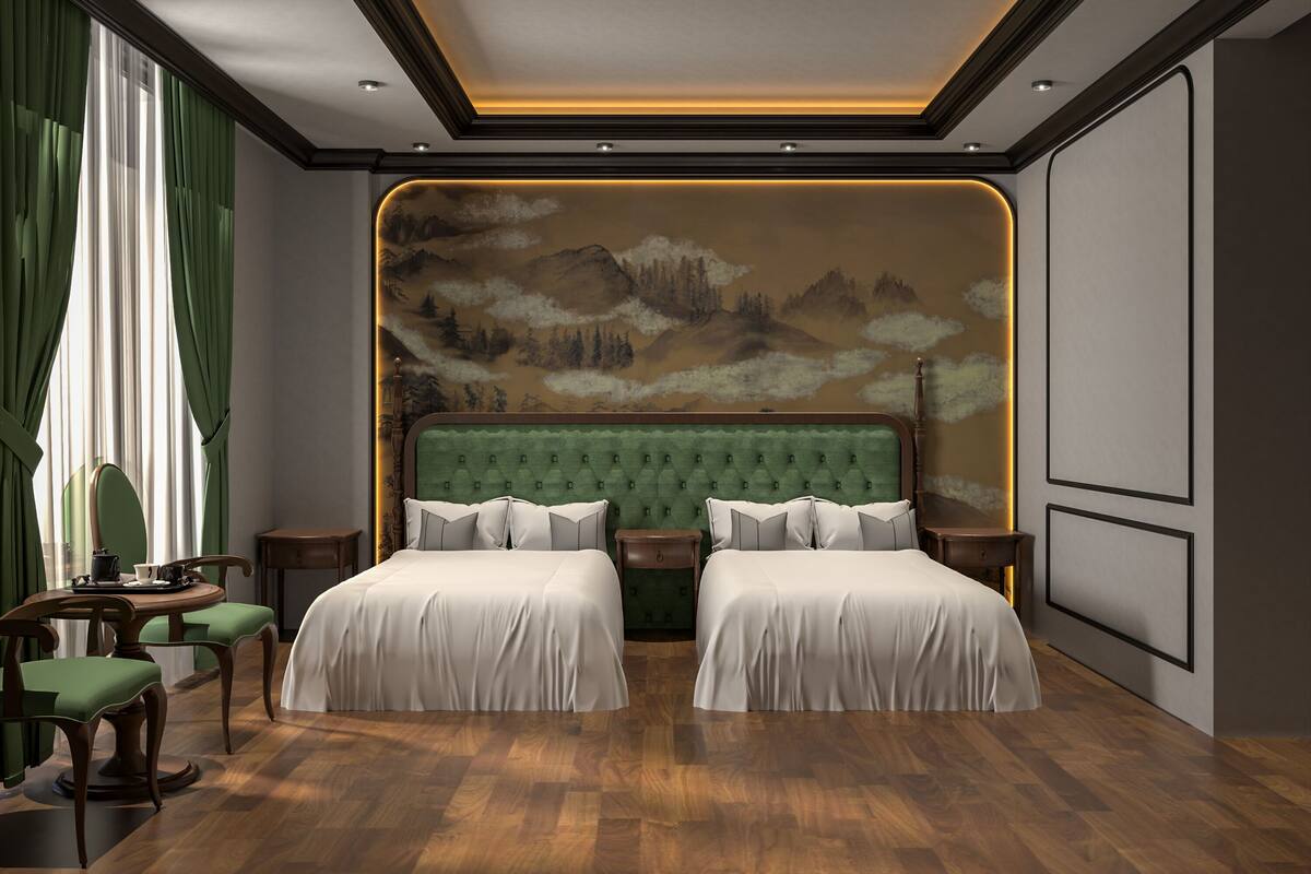 Ein Schlafzimmer mit zwei Betten, Holzboden, einem grünen, gepolsterten Kopfteil und einer Wandmalerei von Bergen.