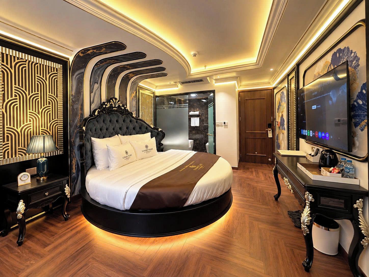 Un dormitorio lujoso con una cama curvada, un televisor y un minibar.