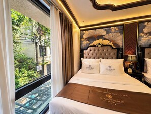 A hotel room with a large bed, a view of greenery outside, and a decorative wall. - Luxury Place Hotel (Hanoi)